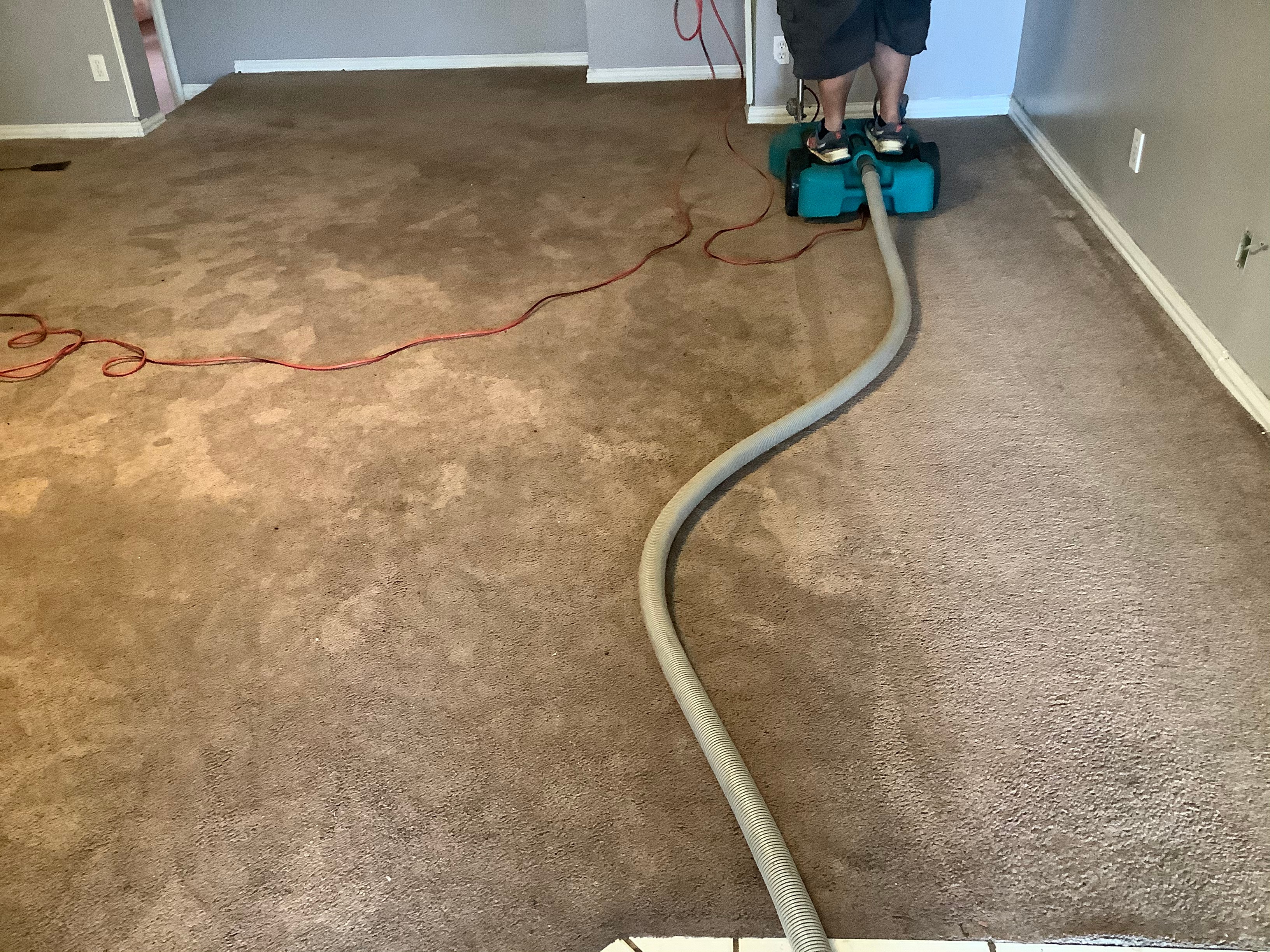 R.G. Pro Floors technician operating industrial water extraction machine removing moisture from saturated carpet after water damage in Central Texas