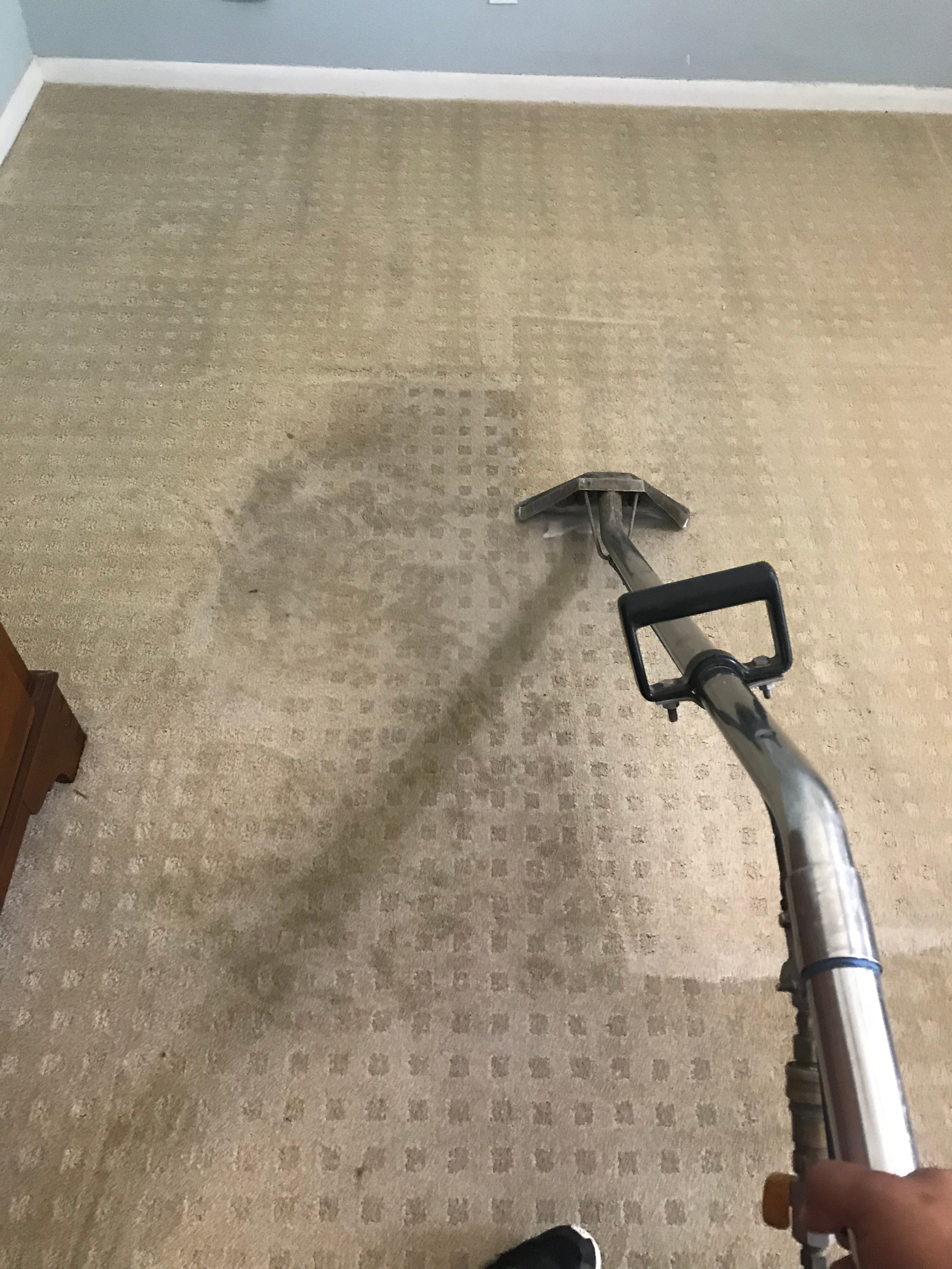 Hot water extraction wand actively steam-cleaning a beige patterned bedroom carpet showing the cleaning path contrast by R.G. Pro Floors in Brownwood TX